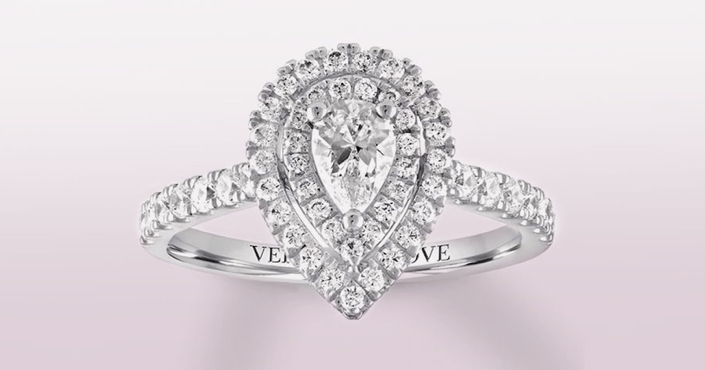 White gold engagement ring with pear shaped center diamond and round diamond double halo on a white background.